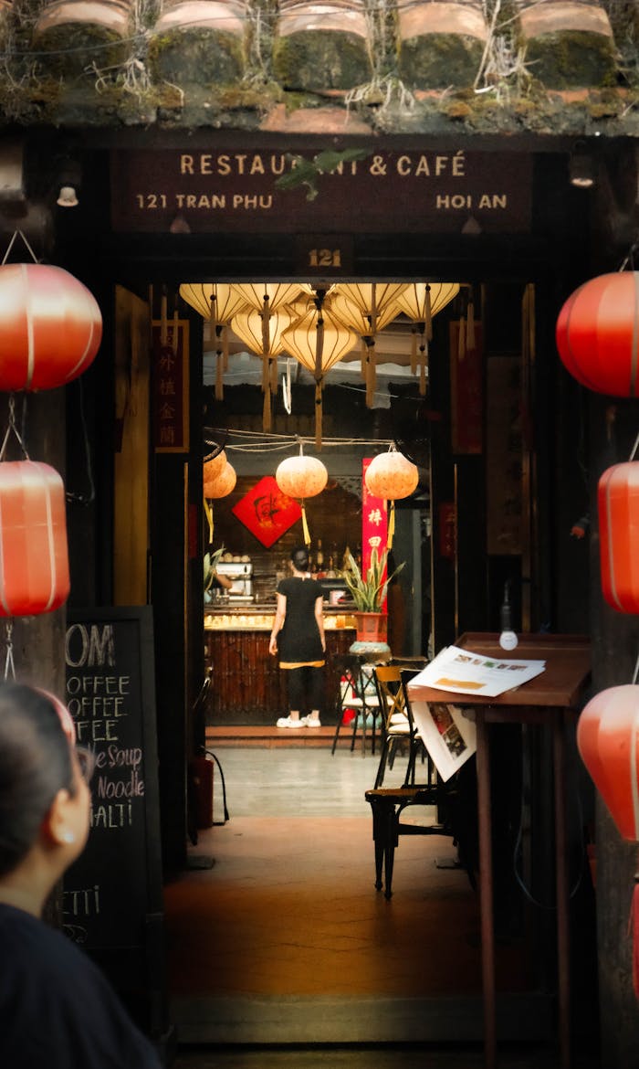 Explore a cozy cafe entrance in Hội An featuring traditional lanterns and wooden architecture.